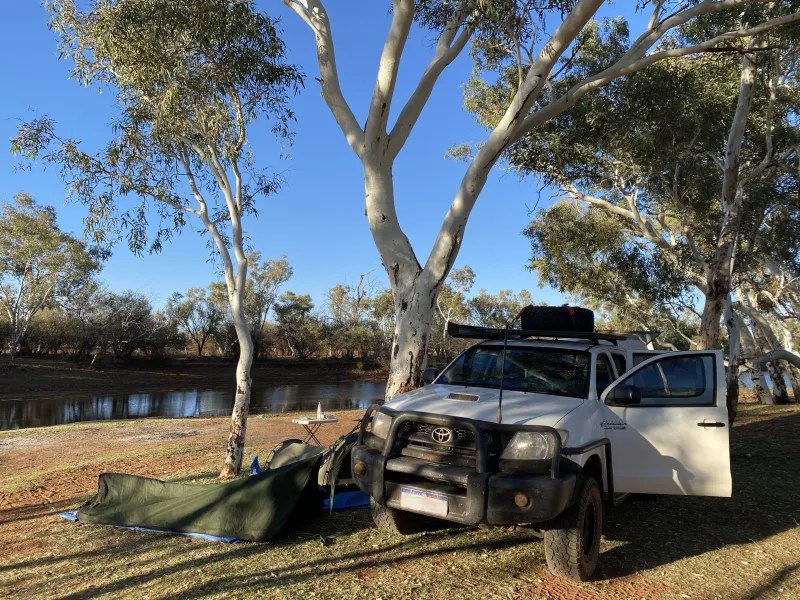 A ute and swag in front of an outback lake